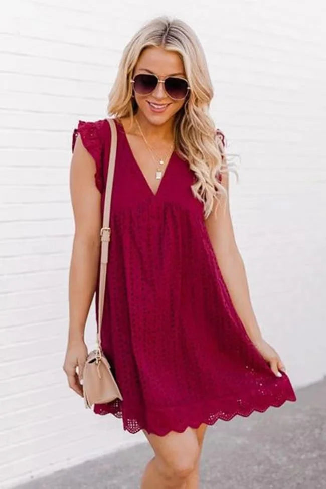 Frau in rotem Sommerkleid mit Spitzenmuster, Sonnenbrille und beiger Handtasche. Perfekt für lässige Sommermode und trendige Outfits.