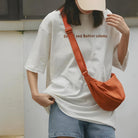 Frau mit weißem Oversize-T-Shirt, roter Umhängetasche, Jeansshorts, lässiger Streetstyle.