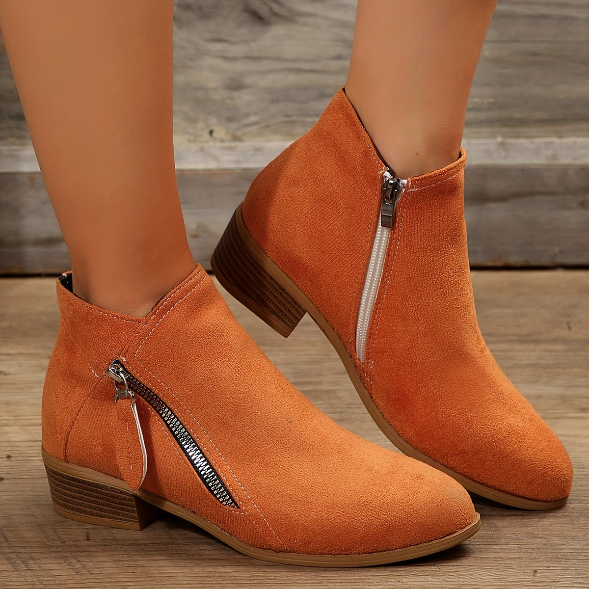 Damen Stiefeletten in Orange mit seitlichem Reißverschluss, flachem Absatz und Wildlederoptik. Perfekt für Herbstmode und lässige Outfits.