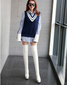 Frau in modischem Outfit mit blauem Pullunder, gestreifter Bluse und weißen Overknee-Stiefeln. Trendige Damenmode, stilvolle Herbstkleidung.