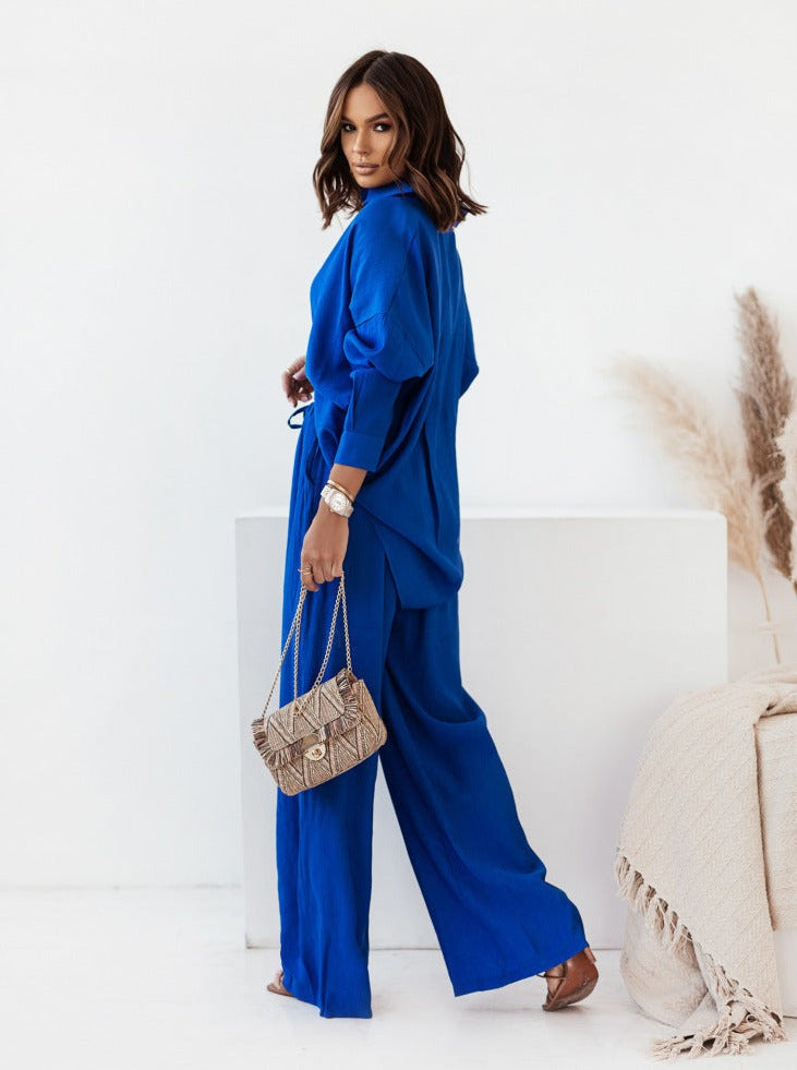 Frau in elegantem, blauem Jumpsuit mit modischer Handtasche. Perfektes Outfit für stilvolle Anlässe. Damenmode, Trend, Fashion, Stil.