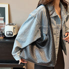 Frau mit schwarzer, geflochtener Ledertasche und Jeansjacke. Modetrend 2023, stilvolle Accessoires, Damenmode, lässiger Look.