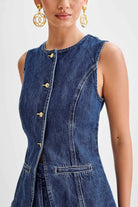 Ärmellose Jeansweste mit goldenen Knöpfen und eleganten Nähten, kombiniert mit auffälligen, goldenen Ohrringen. Perfekt für modische Outfits.