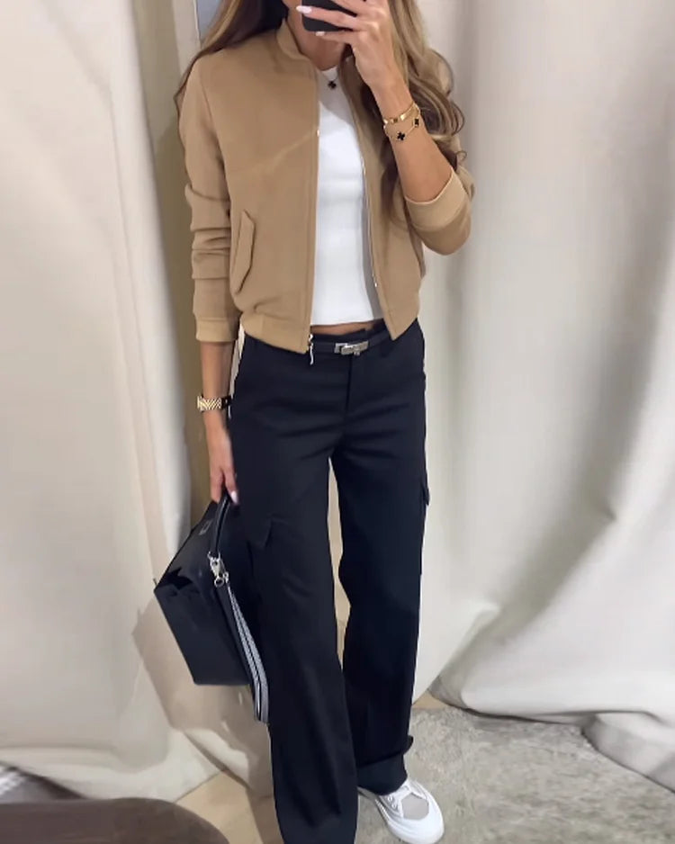 Dame in modischer Freizeitkleidung: beige Jacke, weißes Top, schwarze Hose, weiße Sneaker. Perfekt für stilvolle, lässige Outfits.