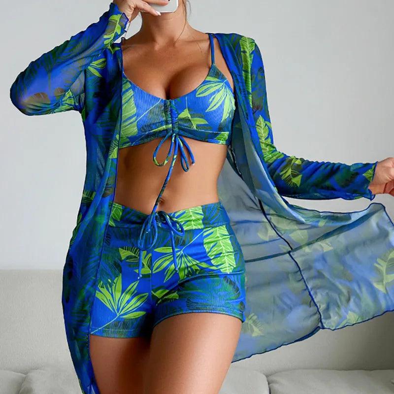 Frau in blau-grünem tropischen Bikini-Set mit passendem transparentem Kimono. Sommermode, Strandbekleidung, tropisches Design, Damenmode.