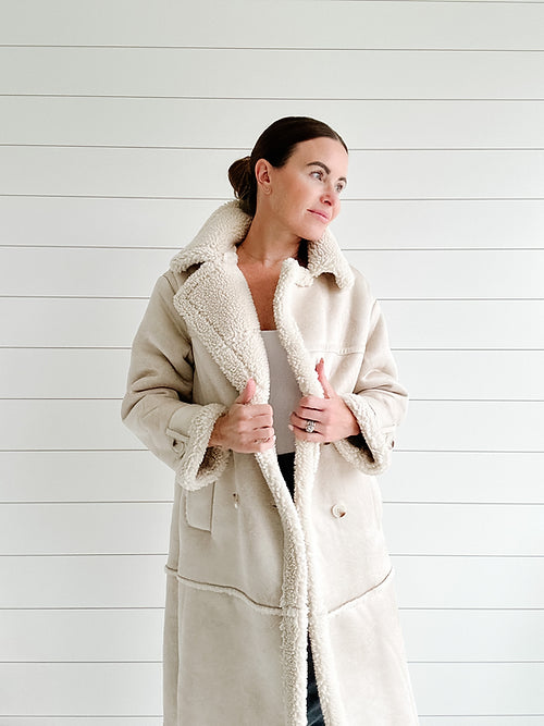 Damenmantel aus beigem Lammfellimitat, warm gefüttert, modisch und elegant, ideal für Wintermode. Perfekt für stilvolle, kalte Tage.