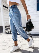 Damenmode: Trendige High-Waist-Jeans mit lockerer Passform, kombiniert mit weißen Sneakers und schwarzer Handtasche. Perfekt für den Sommerlook.