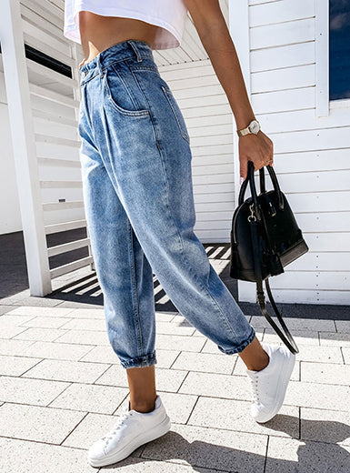 Damenmode: Trendige High-Waist-Jeans mit lockerer Passform, kombiniert mit weißen Sneakers und schwarzer Handtasche. Perfekt für den Sommerlook.