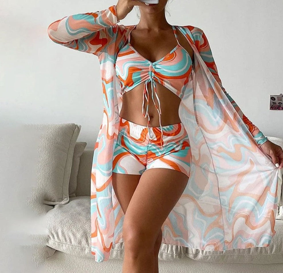 Frau in buntem, gemustertem Strandoutfit mit Kimono, Top und Shorts. Sommermode, Strandkleidung, trendige Bademode, lebendige Farben.