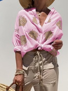 Frau in rosa Bluse mit goldenen Mustern, beige Hose, Strohhut, Sommermode.
