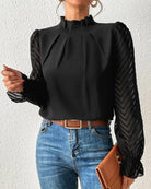 Elegante schwarze Bluse mit transparenten Ärmeln und Chevron-Muster, kombiniert mit blauer Jeans und brauner Clutch. Perfekt für stilvolle Outfits.