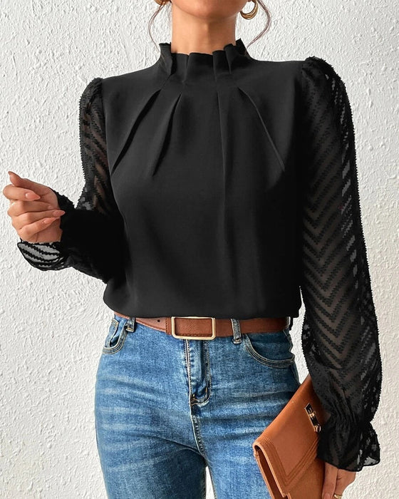 Elegante schwarze Bluse mit transparenten Ärmeln und Chevron-Muster, kombiniert mit blauer Jeans und brauner Clutch. Perfekt für stilvolle Outfits.
