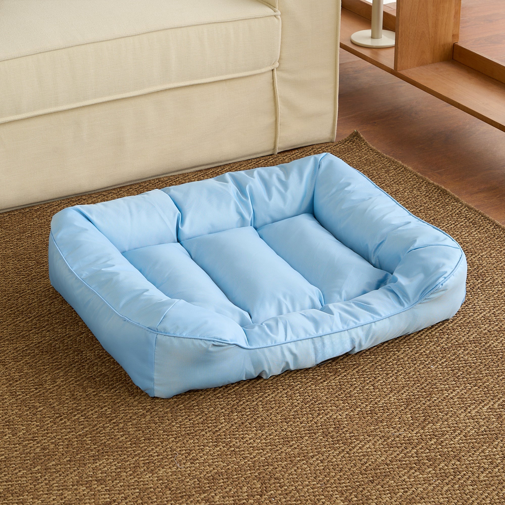 Wasserdichtes, kühlendes Haustierbett, mittelgroß, blau, auf Teppich vor Sofa.