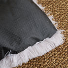 Graue rutschfeste Haustiermatte mit weißem Plüschrand auf geflochtenem Teppich.