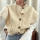 Damen Strickweste in Creme mit Zopfmuster und Holzknöpfen, kombiniert mit weißer Bluse und Jeans. Modetrend, Herbstmode, Strickmode.