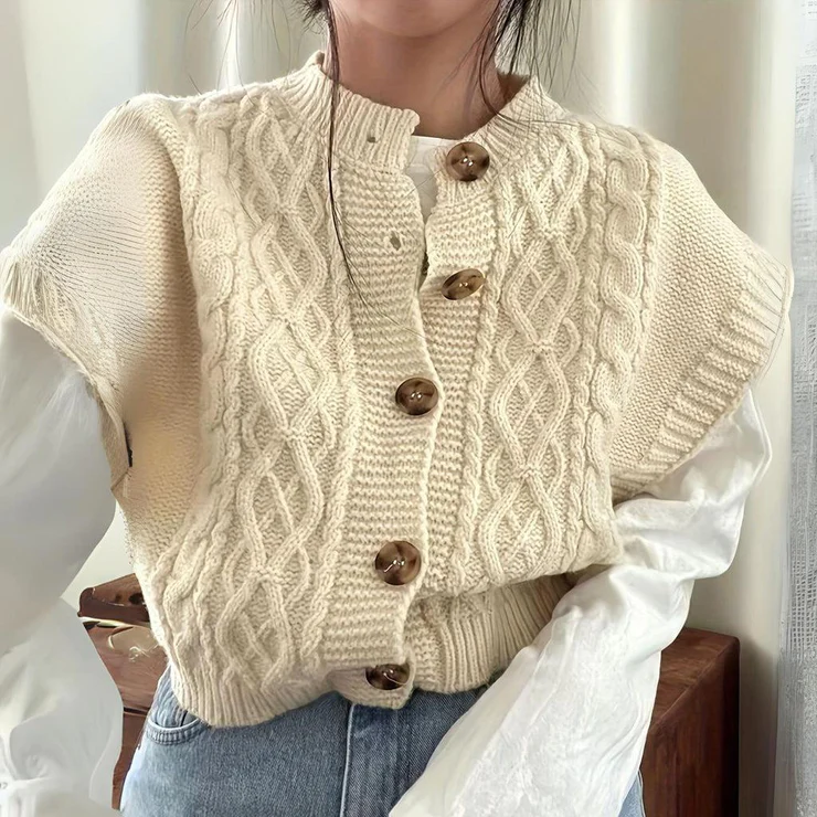 Damen Strickweste in Creme mit Zopfmuster und Holzknöpfen, kombiniert mit weißer Bluse und Jeans. Modetrend, Herbstmode, Strickmode.