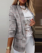 Damen-Blazer mit Hahnentrittmuster, kombiniert mit weißer Spitzenbluse und goldenen Accessoires. Eleganter Business-Look für stilvolle Frauen.