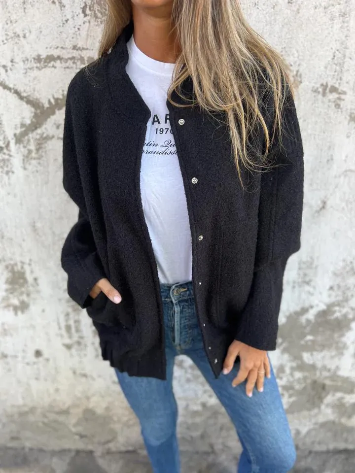 Frau trägt schwarze Strickjacke, weiße T-Shirt und blaue Jeans. Modetrend, lässiger Look, Damenmode, Herbstoutfit, Streetstyle.