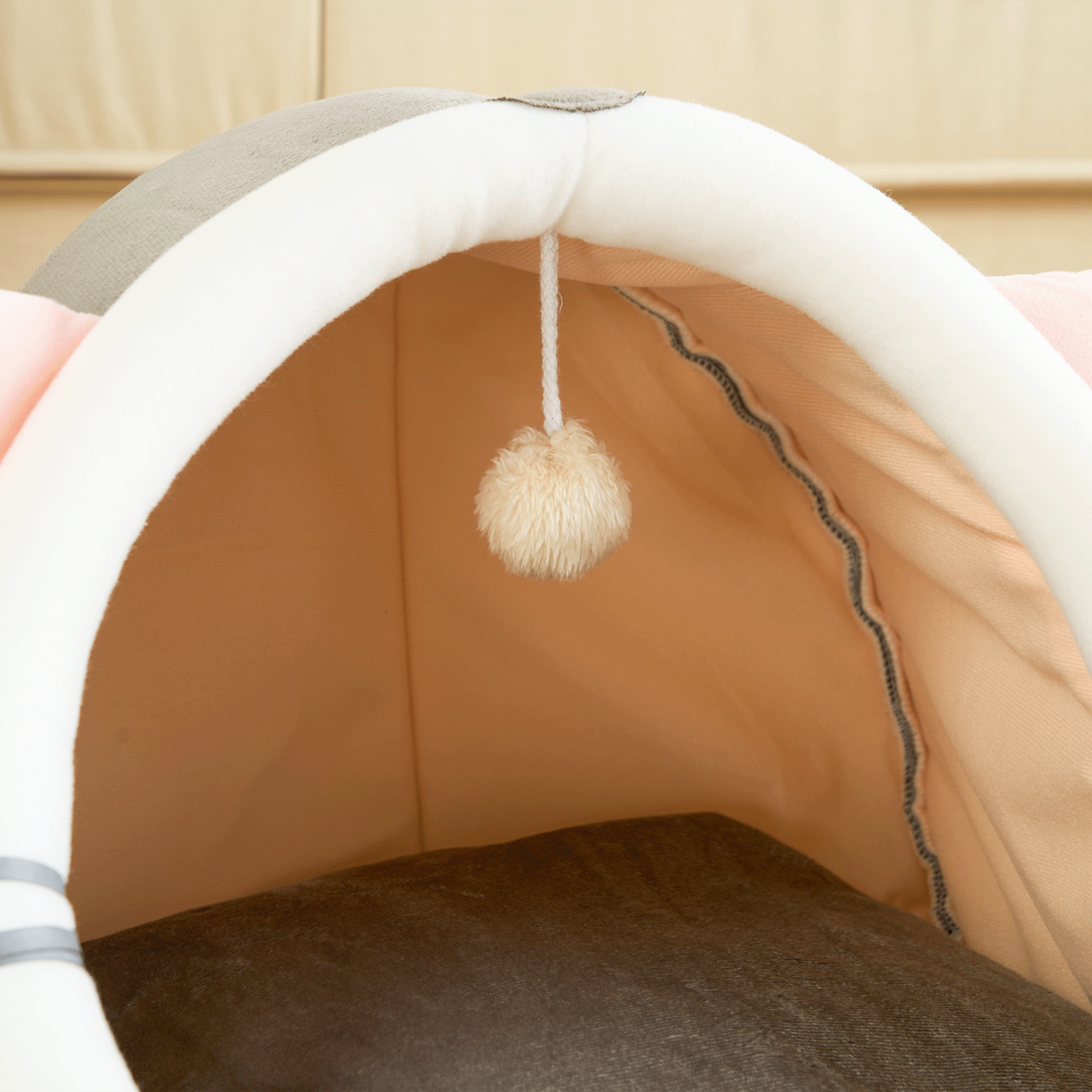 Katzenhöhle aus Stoff mit Spielzeug, beige und grau, gemütlicher Rückzugsort für Katzen.