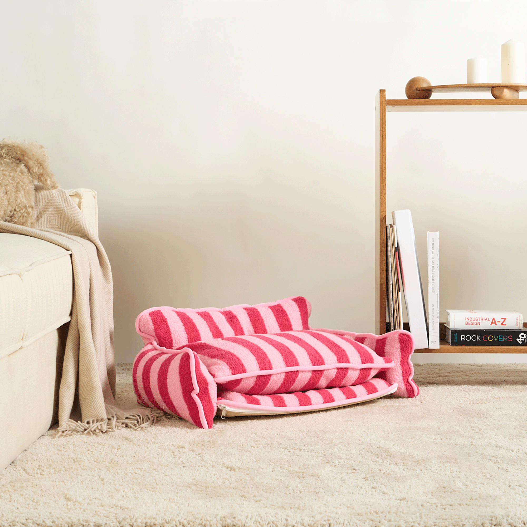Rosa-weiß gestreiftes Katzenbett aus Lammwolle auf Teppich, modernes Wohnzimmer-Design.