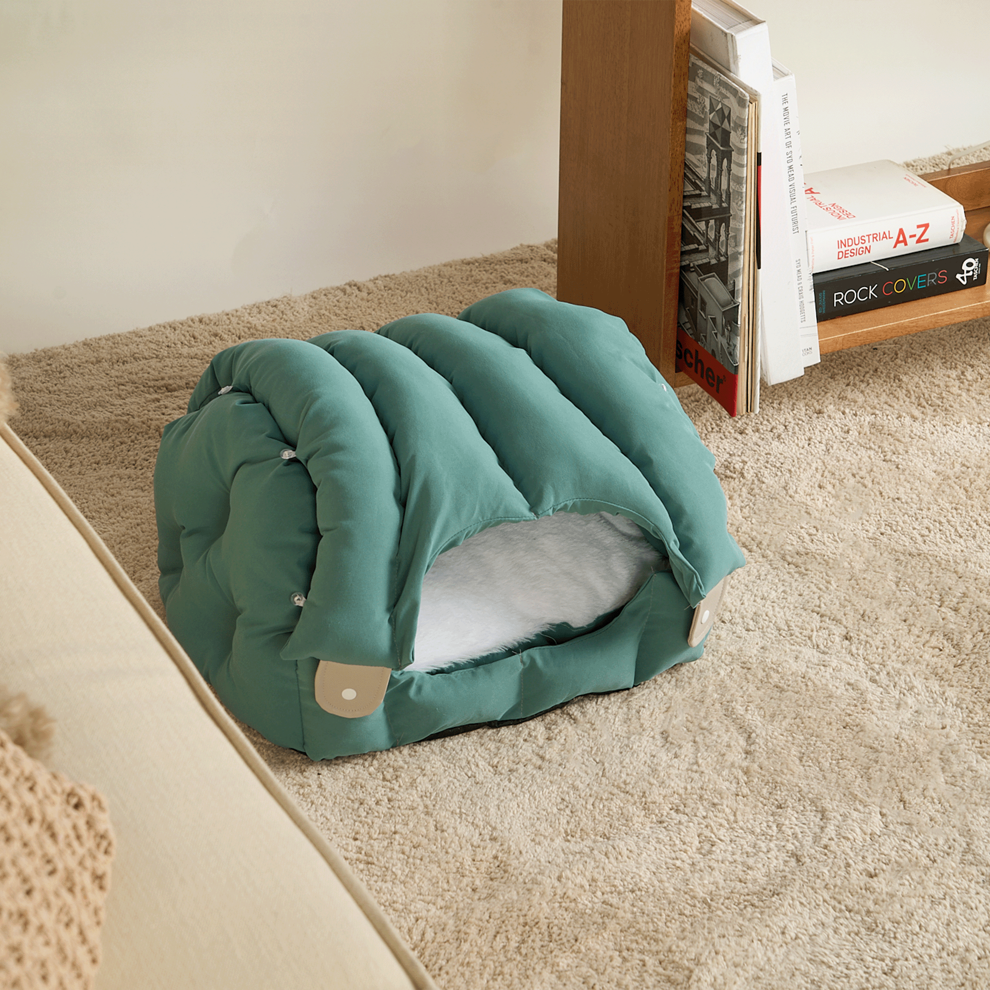 Grünes Katzenbett aus Stoff, gemütlich, auf Teppich, modernes Design, ideal für Haustiere.
