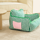 Grünes gestreiftes Haustiersofa aus Plüsch auf Teppich, gemütliches Hundebett, modernes Design.