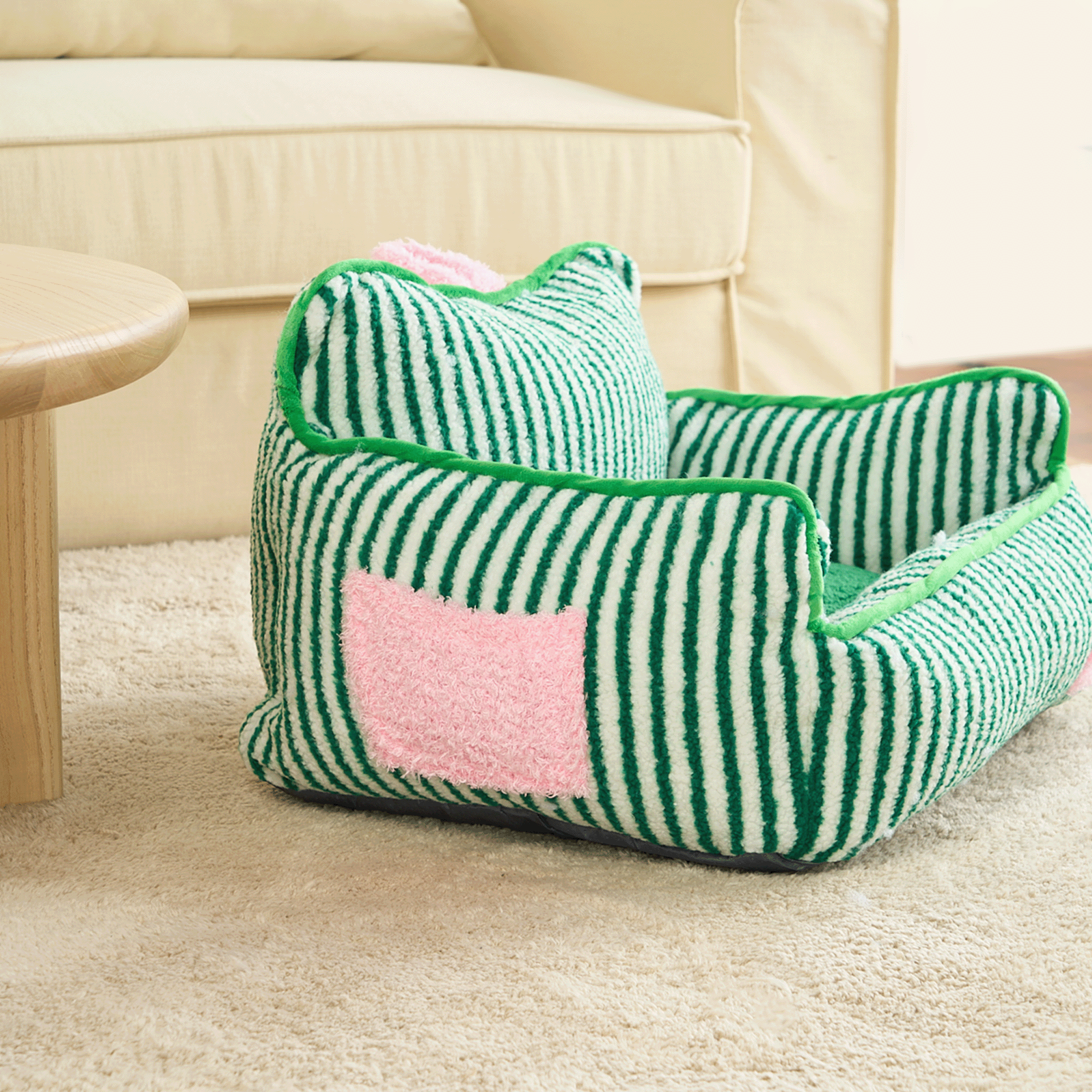 Grünes gestreiftes Haustiersofa aus Plüsch auf Teppich, gemütliches Hundebett, modernes Design.
