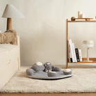 Grauer Plüsch-Bär Spielmatte auf Teppich im Wohnzimmer, ideal für Babyspielzeit.