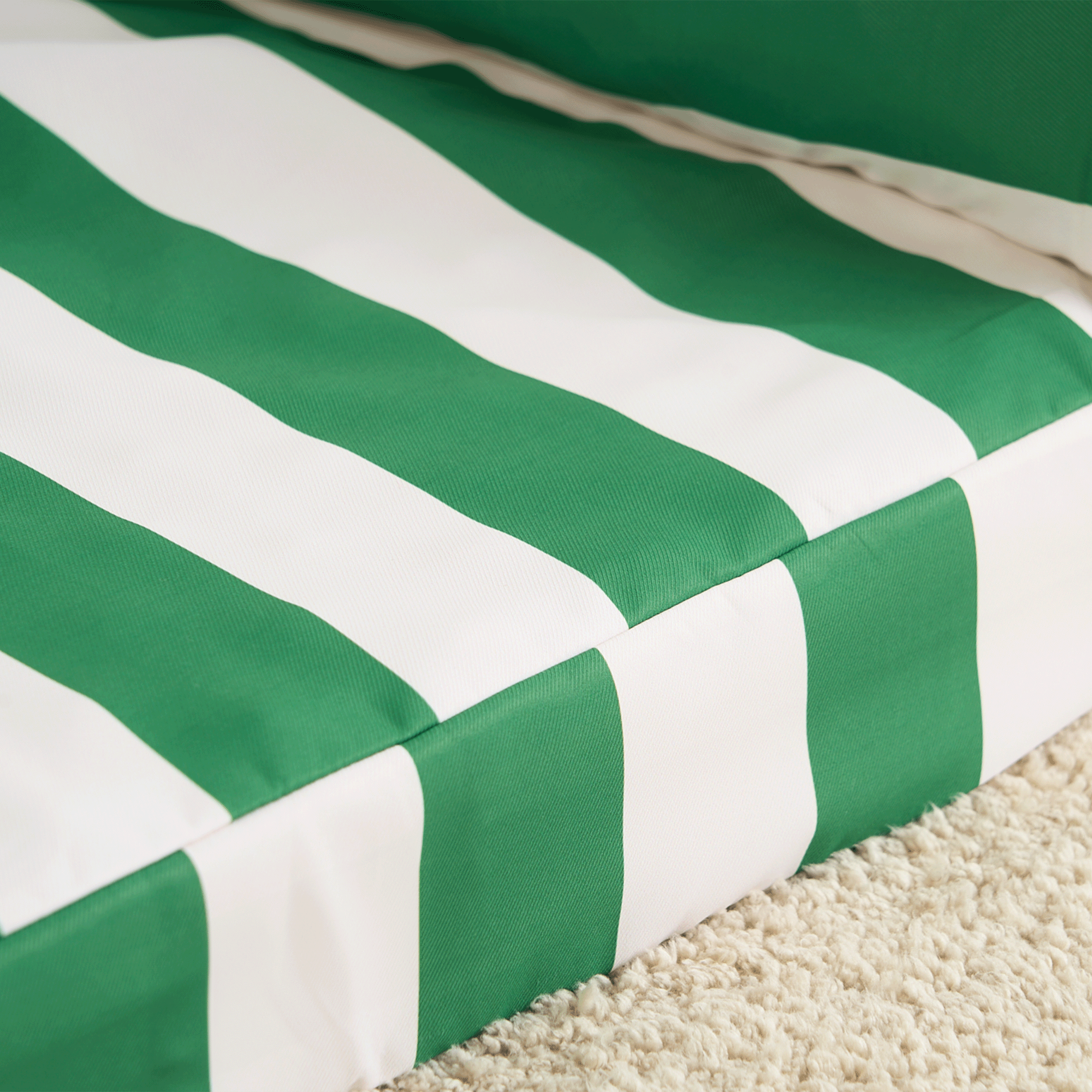 Grün-weiß gestreiftes Haustiersofa auf Teppich, modernes Design, bequeme Tiermöbel.