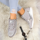 Damen Sneaker in Silber auf flauschigem Teppich, kombiniert mit zerrissenen Jeans. Modische Schuhe, ideal für trendige Freizeitlooks.