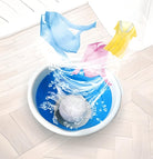 Waschmaschine mit rotierendem Wasser, blauer Trommel und schwebender Kleidung, energieeffizient.