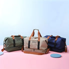 Drei Reisetaschen aus Stoff in Grün, Beige und Blau mit braunen Griffen auf rosa und blauem Hintergrund.