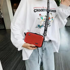 Frau mit roter Umhängetasche, lässiges Outfit, bedrucktes T-Shirt, Jeans, modisch, urban.