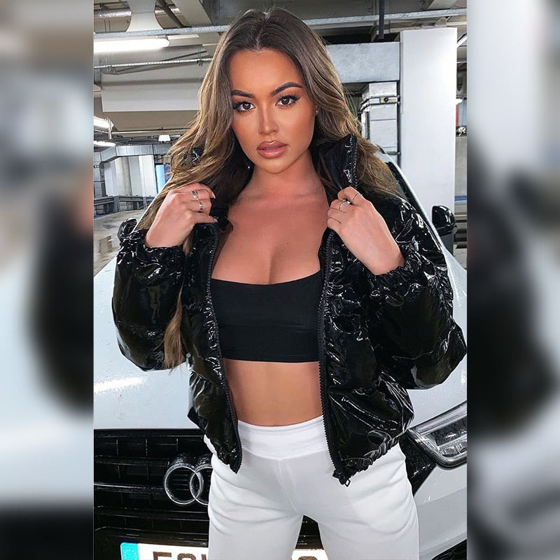 Schwarze Lackjacke, schwarze Crop-Top, weiße Hose, Frau vor Audi. Modetrend, urbaner Stil, stilvolle Damenbekleidung, Auto-Hintergrund.
