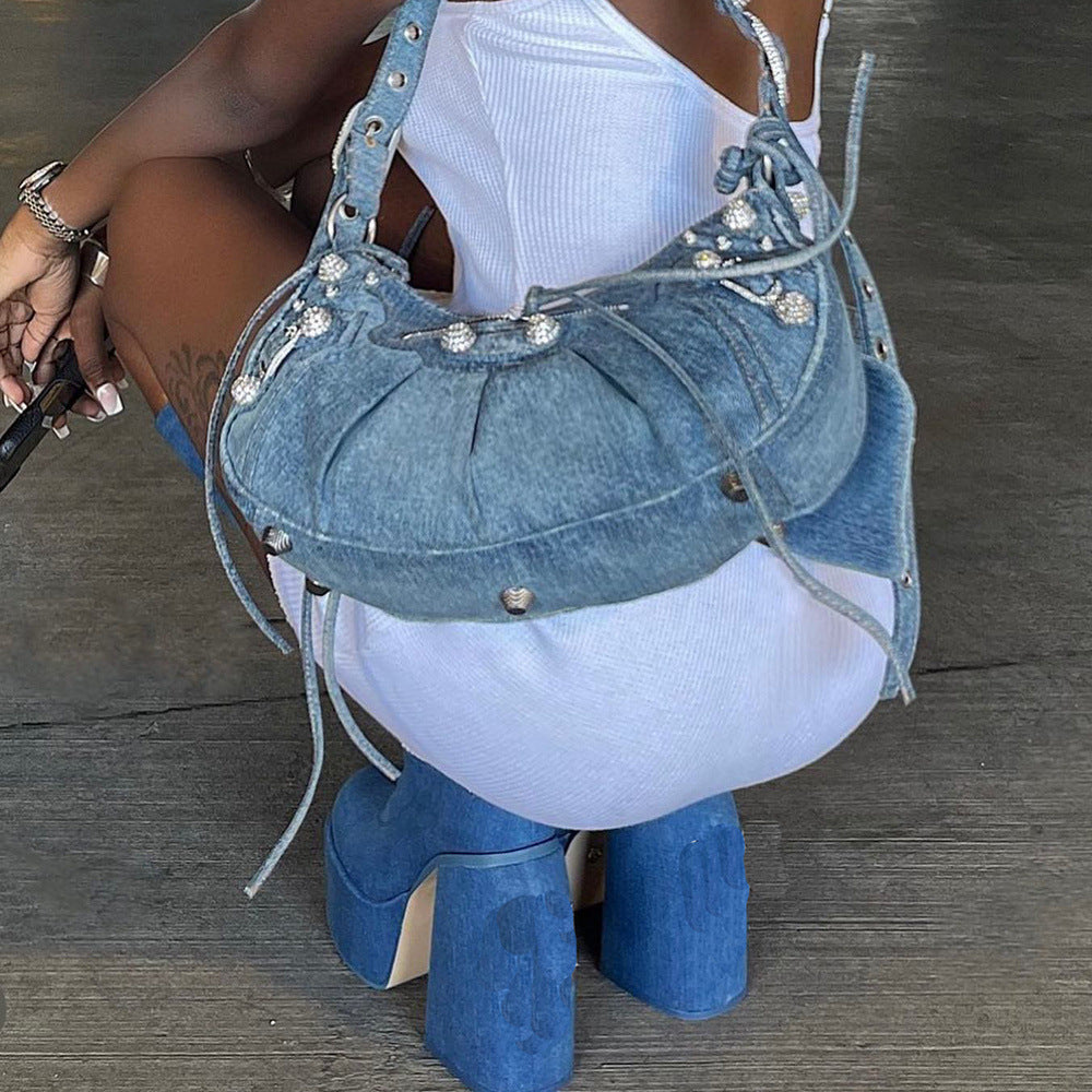 Blaue Jeans-Handtasche mit Nieten und Schnürdetails, kombiniert mit blauen Plateau-Stiefeln. Modisches Accessoire für trendige Outfits.