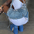 Blaue Jeans-Handtasche mit Nieten und Schnürdetails, kombiniert mit blauen Plateau-Stiefeln. Modisches Accessoire für trendige Outfits.