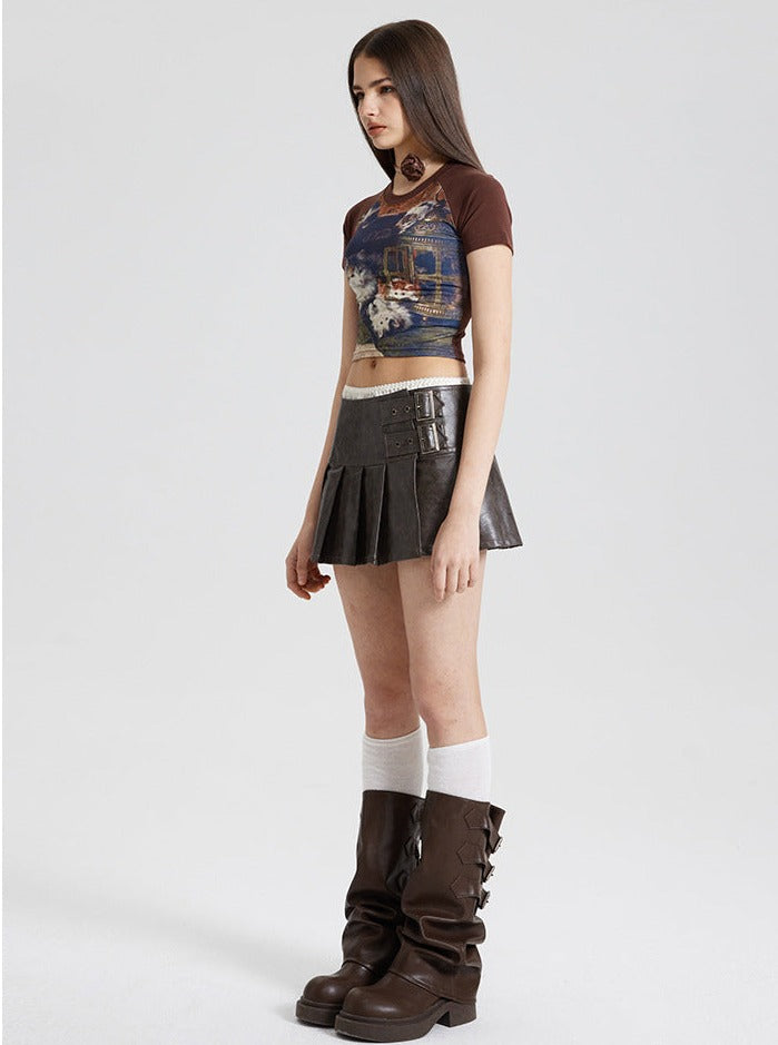 Frau in modischem Outfit: braunes Crop-Top mit Print, schwarzer Faltenrock, hohe Stiefel. Trendige Damenmode, urbaner Stil, Streetwear.