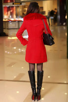 Frau im eleganten roten Mantel mit Pelzkragen, schwarze Stiefel und Handtasche. Mode, Winterkleidung, Damenbekleidung, stilvoller Look.