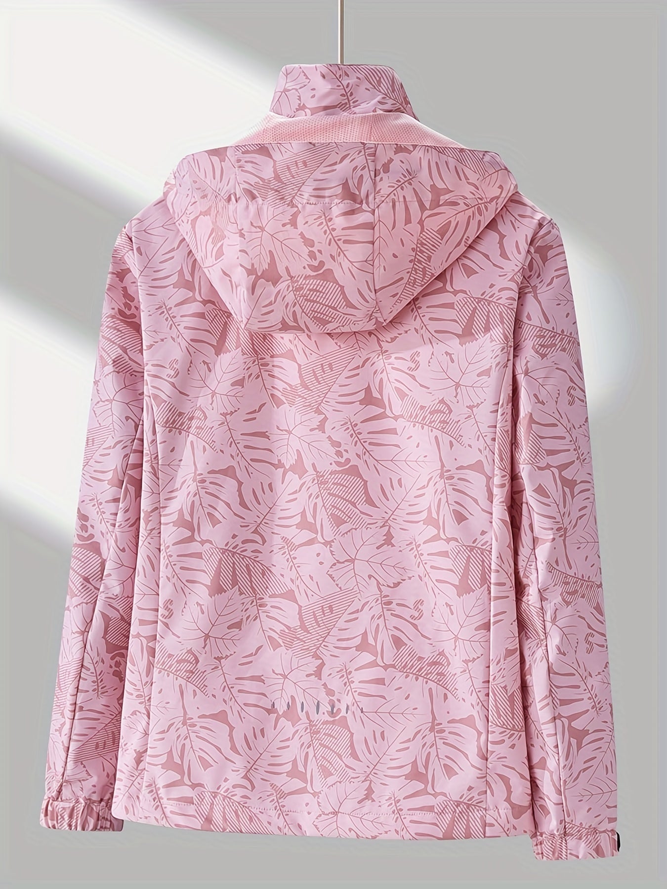 Damen-Regenjacke in Rosa mit tropischem Blattmuster, wasserdicht und atmungsaktiv. Perfekt für Outdoor-Aktivitäten und modische Regenbekleidung.