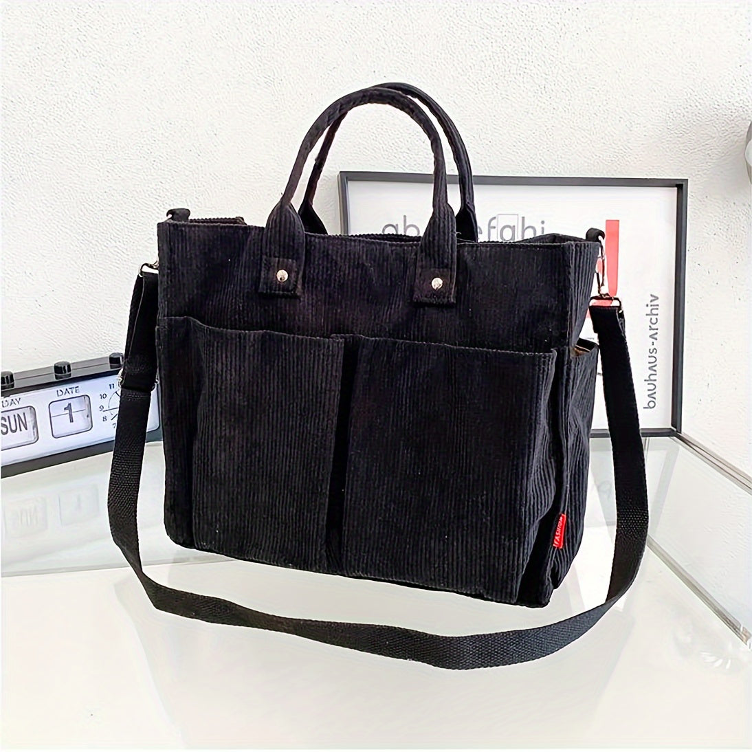 Schwarze Cord-Umhängetasche mit Tragegriffen, ideal für Damen. Stilvolle Handtasche, perfekt für Alltag und Büro. Modische Accessoires.