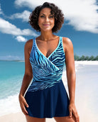 Frau im blauen Badeanzug mit Zebramuster am Strand, lächelnd vor tropischem Meer und Himmel. Sommermode, Strandkleidung, Urlaub, Damenmode.