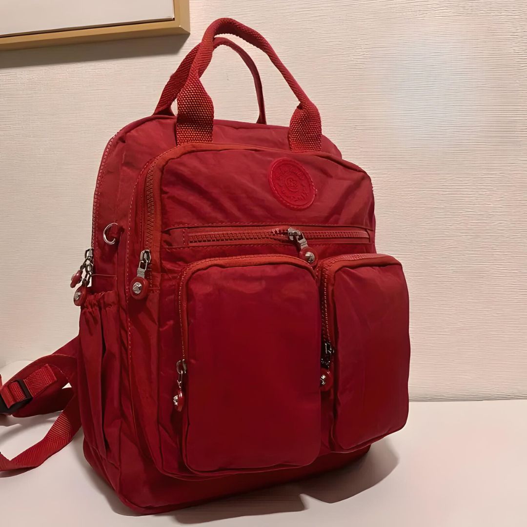 Roter Rucksack mit mehreren Taschen, Reißverschlüssen, ideal für Reisen und Alltag.
