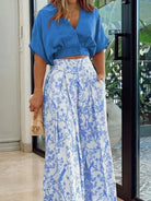 Frau in blauem Oberteil und weiß-blauem Maxirock mit Blumenmuster, Sommermode, elegant.