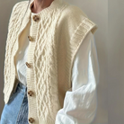 Damen Strickweste beige, Zopfmuster, Holzknöpfe, über weißer Bluse, modisch, elegant, Herbstmode, lässig, zeitloser Stil, hochwertige Qualität.