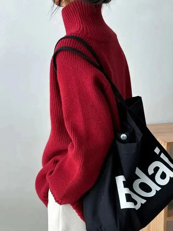 Roter Rollkragenpullover aus Strick, kombiniert mit schwarzer Stofftasche. Modetrend, Herbstmode, Damenbekleidung, lässiger Stil.