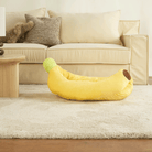 Gelbes Bananen-Sofa-Haustierbett auf beigem Teppich vor cremefarbenem Sofa im Wohnzimmer.