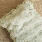 Flauschiges, beruhigendes Kissen in Cremefarbe auf Teppich, ideal für Entspannung und Komfort.