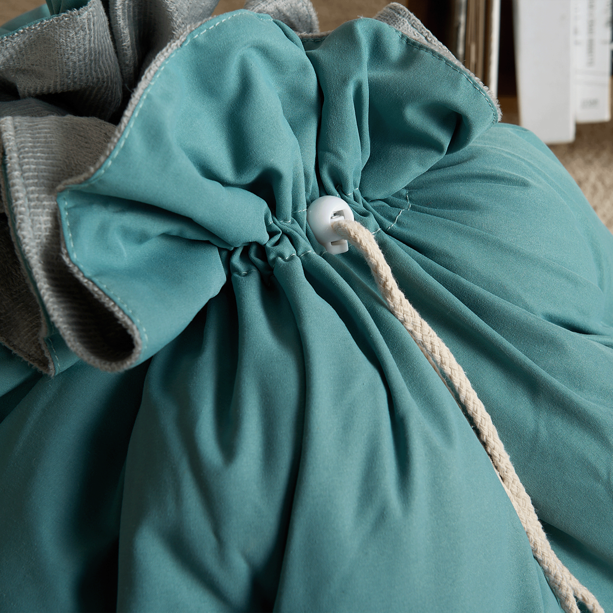Türkiser Sitzsack mit Kordelzug, weicher Stoff, gemütliches Wohnaccessoire.