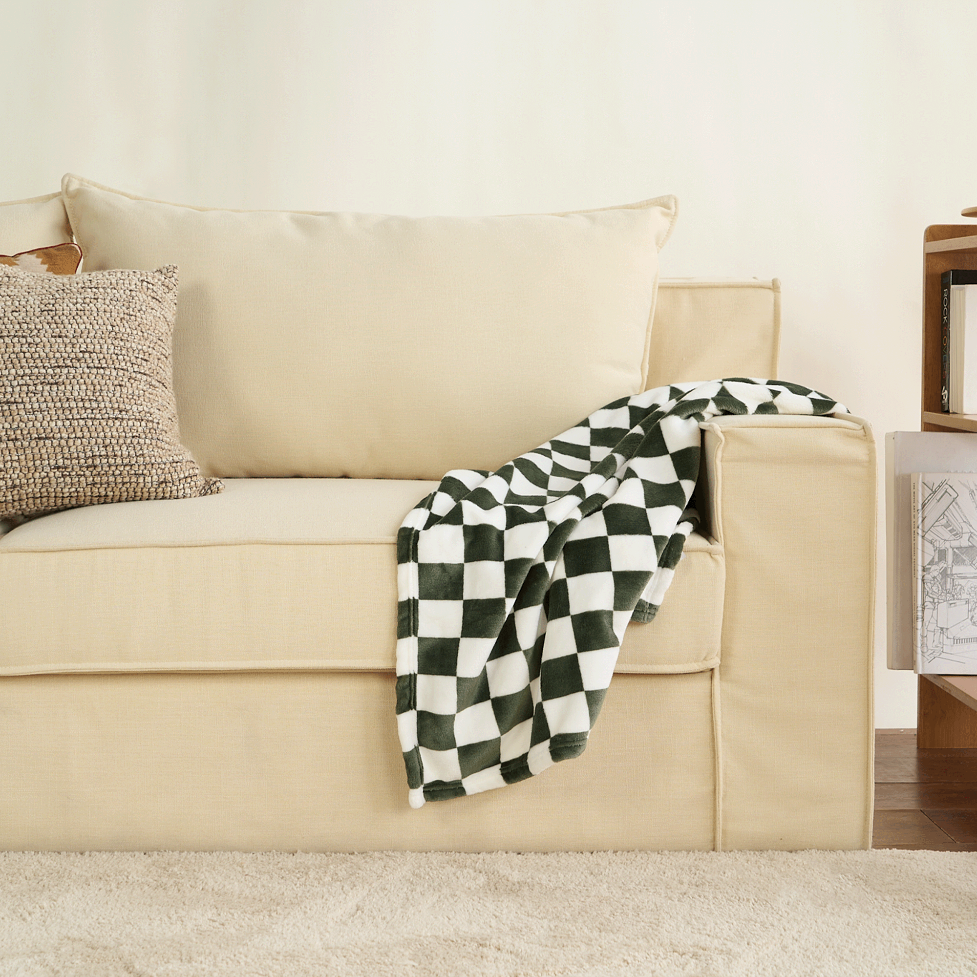 Schwarz-weiß karierte Flanell-Haustierdecke auf beigem Sofa im Wohnzimmer.