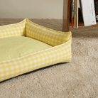 Gelbes kariertes Hundebett, abnehmbar, gemütlich, auf Teppich, modernes Design.